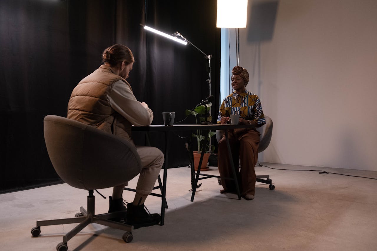 A man and woman recording a podcast in a professional studio environment.